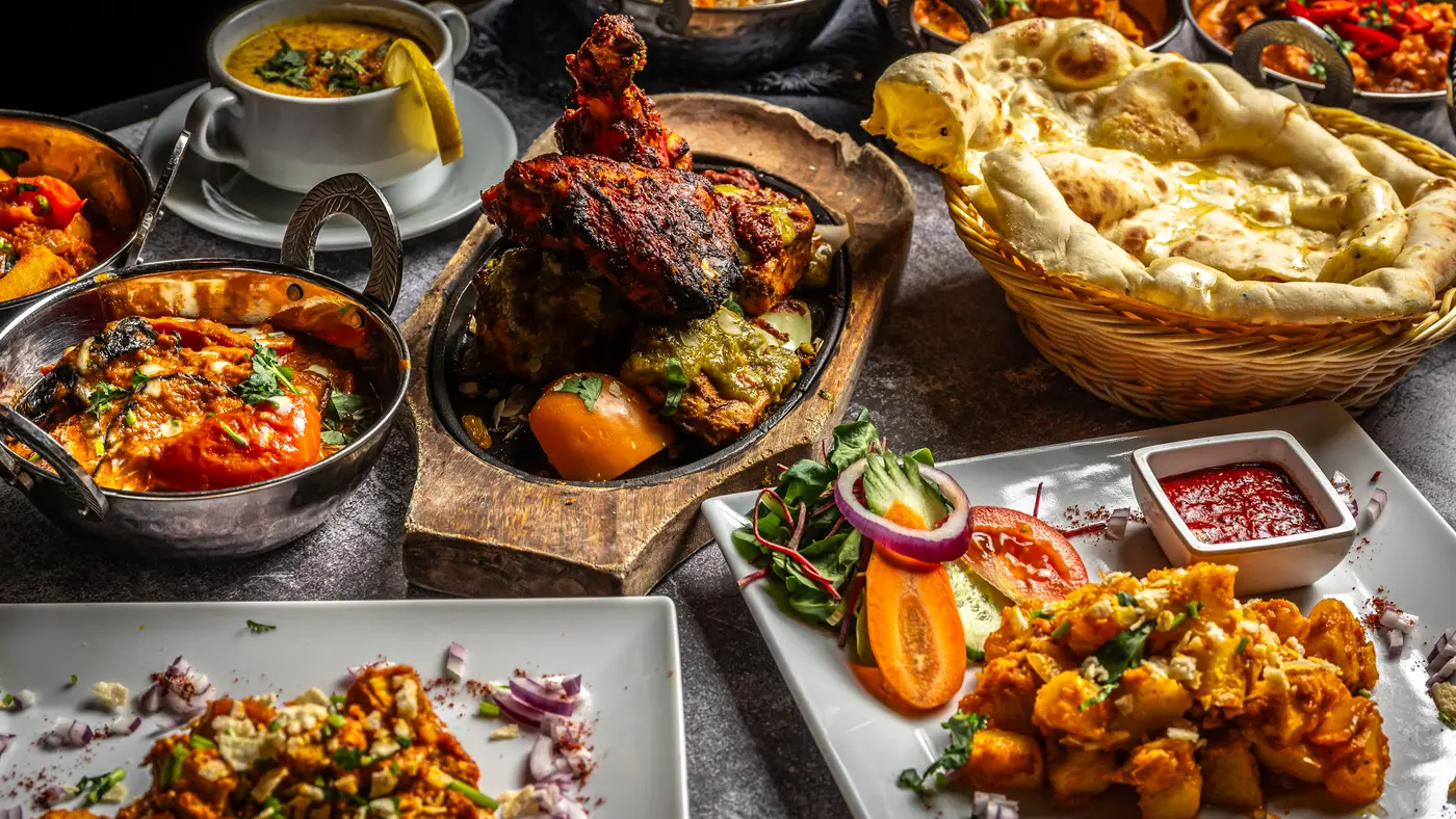 Een gedekte tafel vol Indiase gerechten: biryani, curry's, naan en schalen met voorgerechten